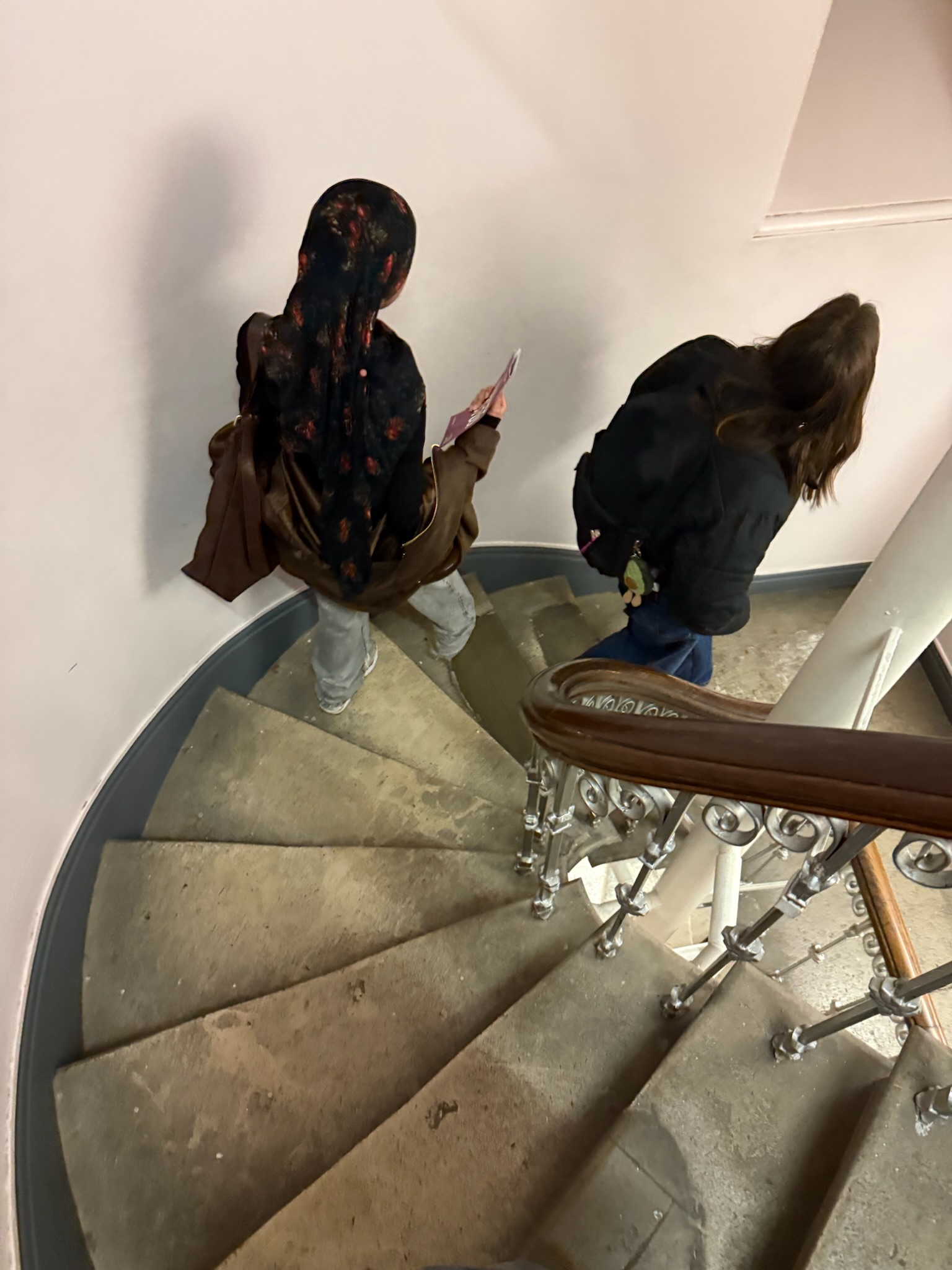 two students walking down narrow circular stairs